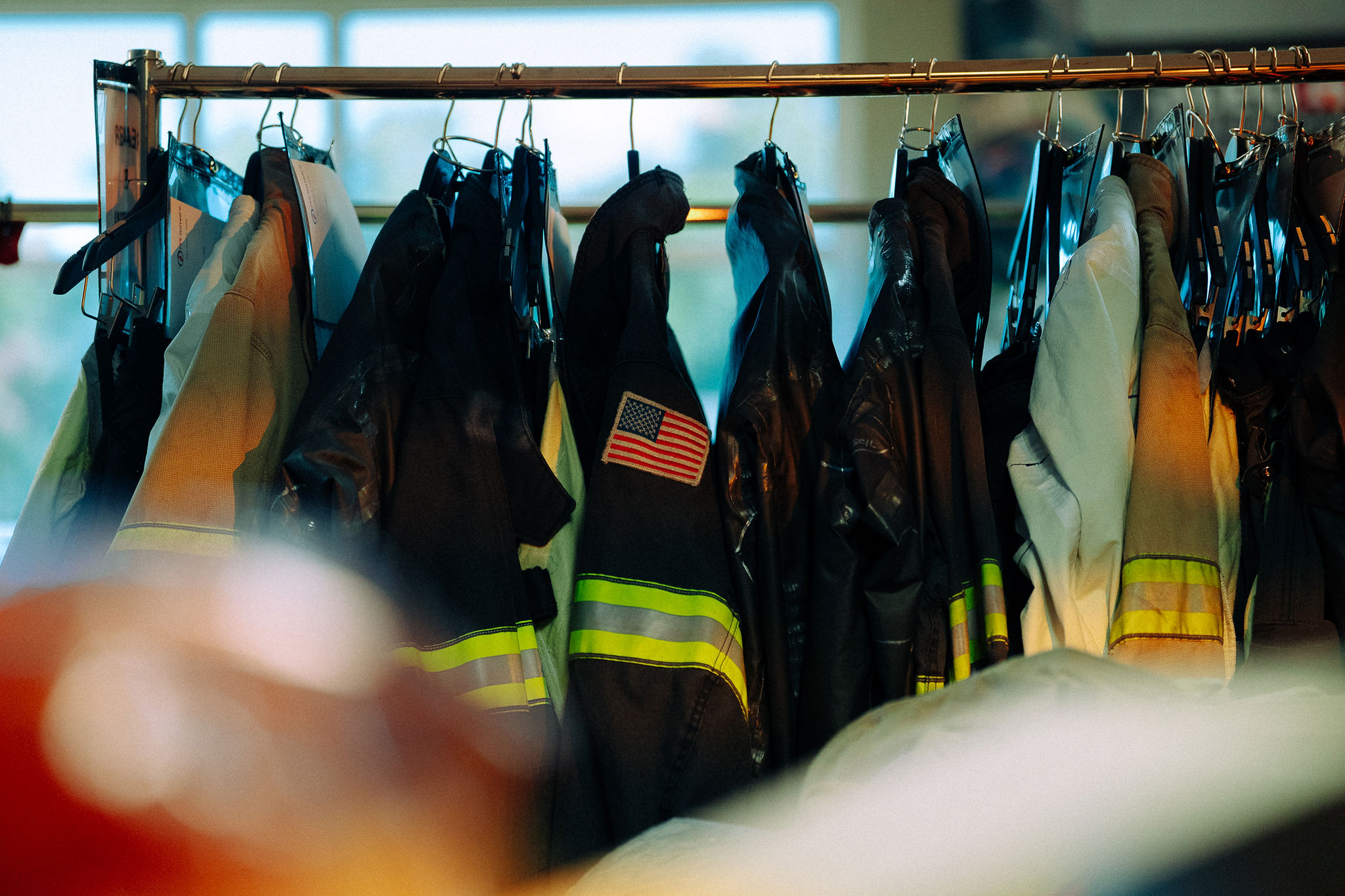 Turnout gear hanging on a rack, an American flag patch on one sleeve