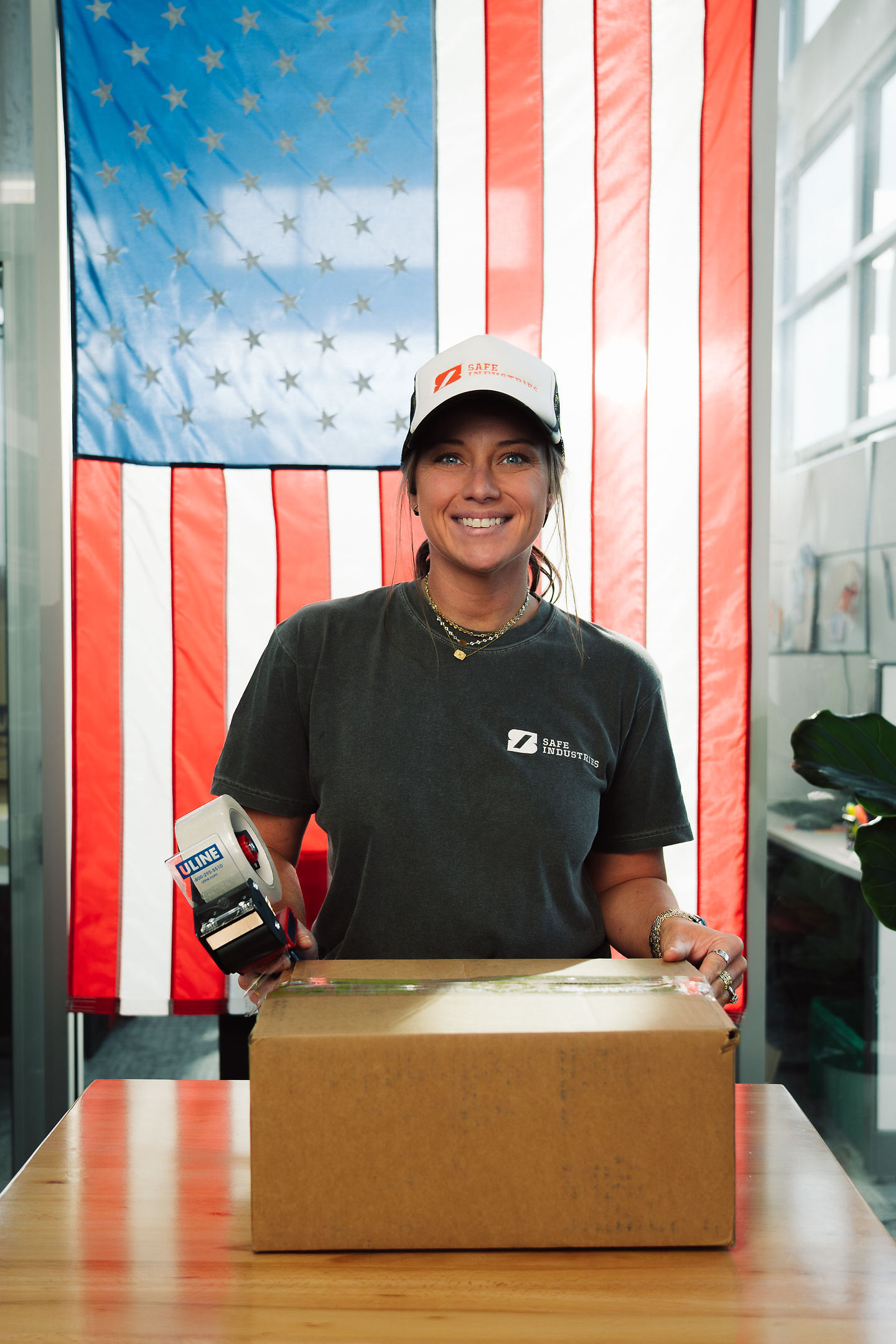 A teammate taping up a customer shipment in front of the American flag