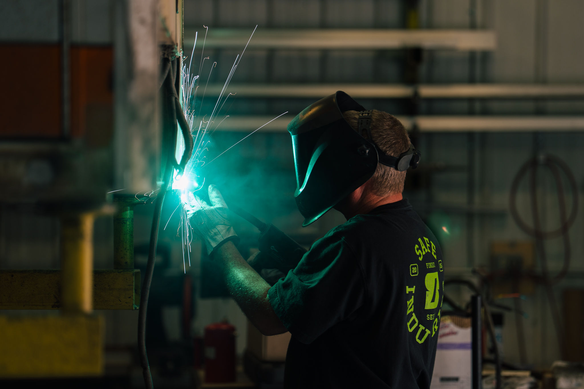 A Safe Industries fabricator welding in the shop, sparks lighting the dark