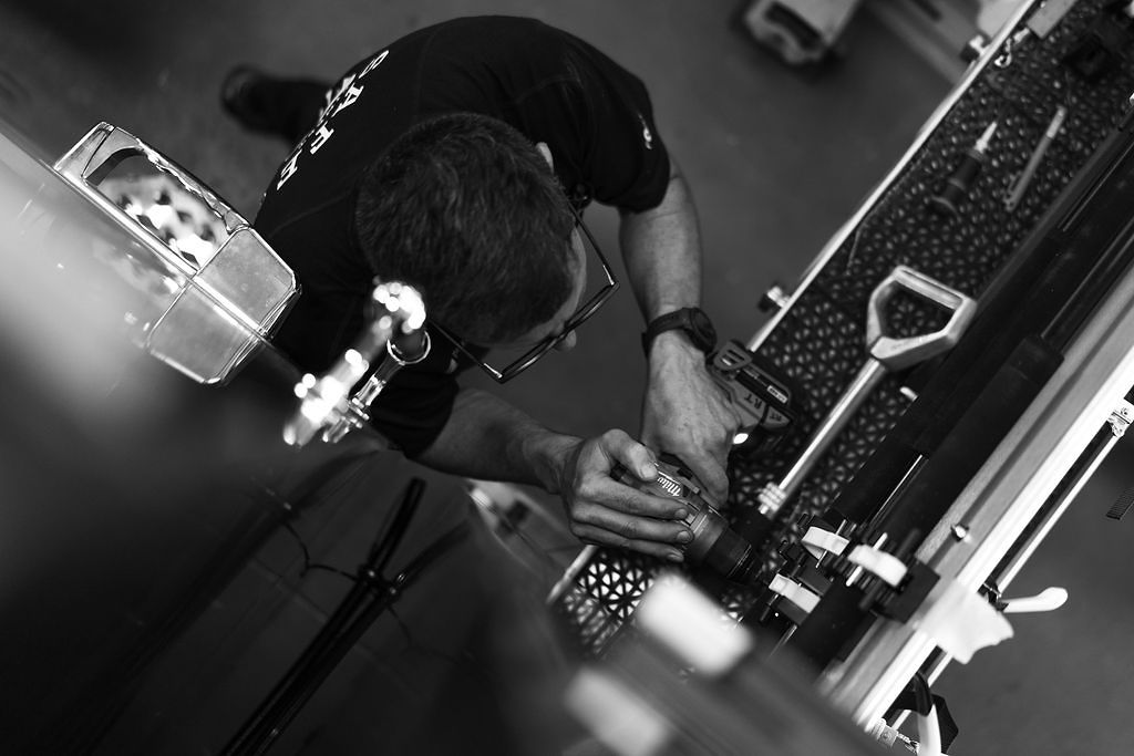 A technician running a drill on an apparatus body, in black and white